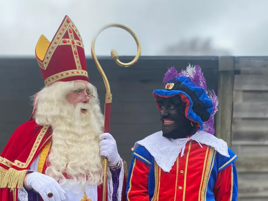 Sinterklaas en Zwarte Piet kijken elkaar vrolijk aan